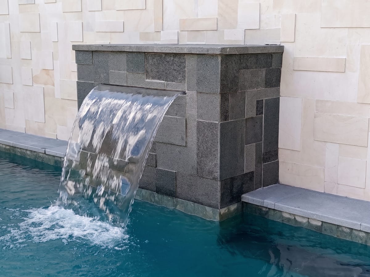Carved stone water feature beside a villa pool in Bali